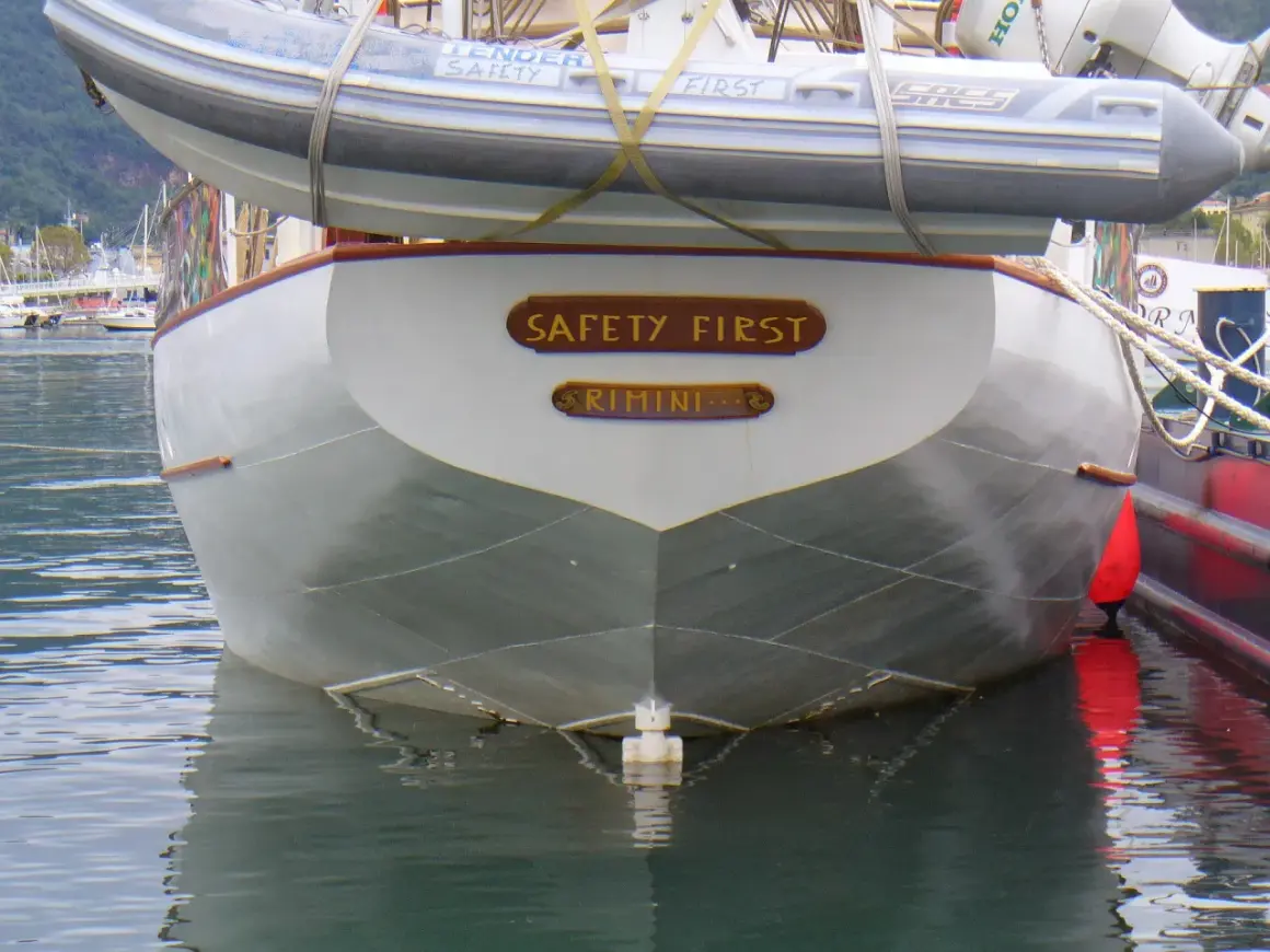 La poppa di una barca con la scritta "SAFETY FIRST RIMINI". Il suo mascone, simbolo di sicurezza, è ben visibile.