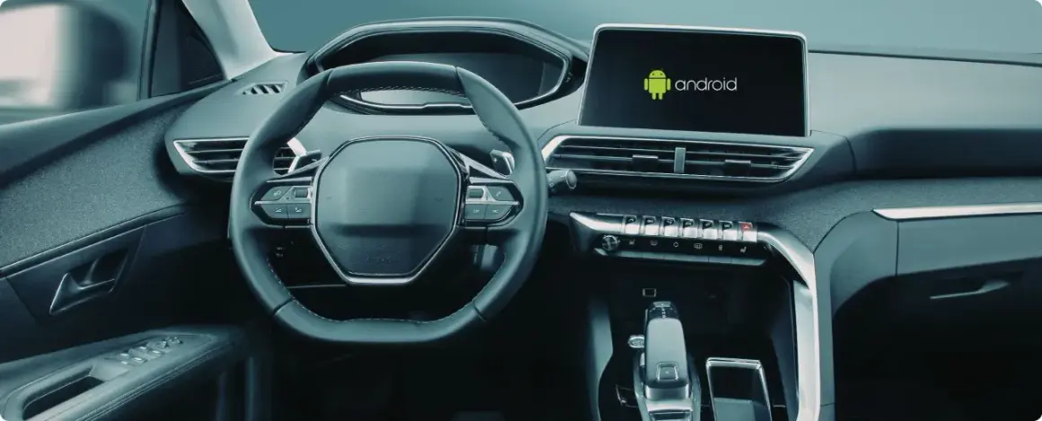 Wnętrze samochodu z widocznym ekranem multimedialnym z logo Android. Dowiedz się, jak włączyć Android Auto.