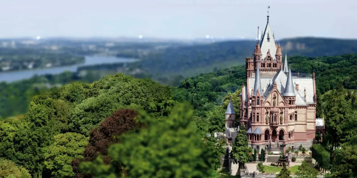 Schloss Drachenburg thront majestätisch inmitten üppiger Wälder, mit Türmchen und Zinnen, die in den Himmel ragen.