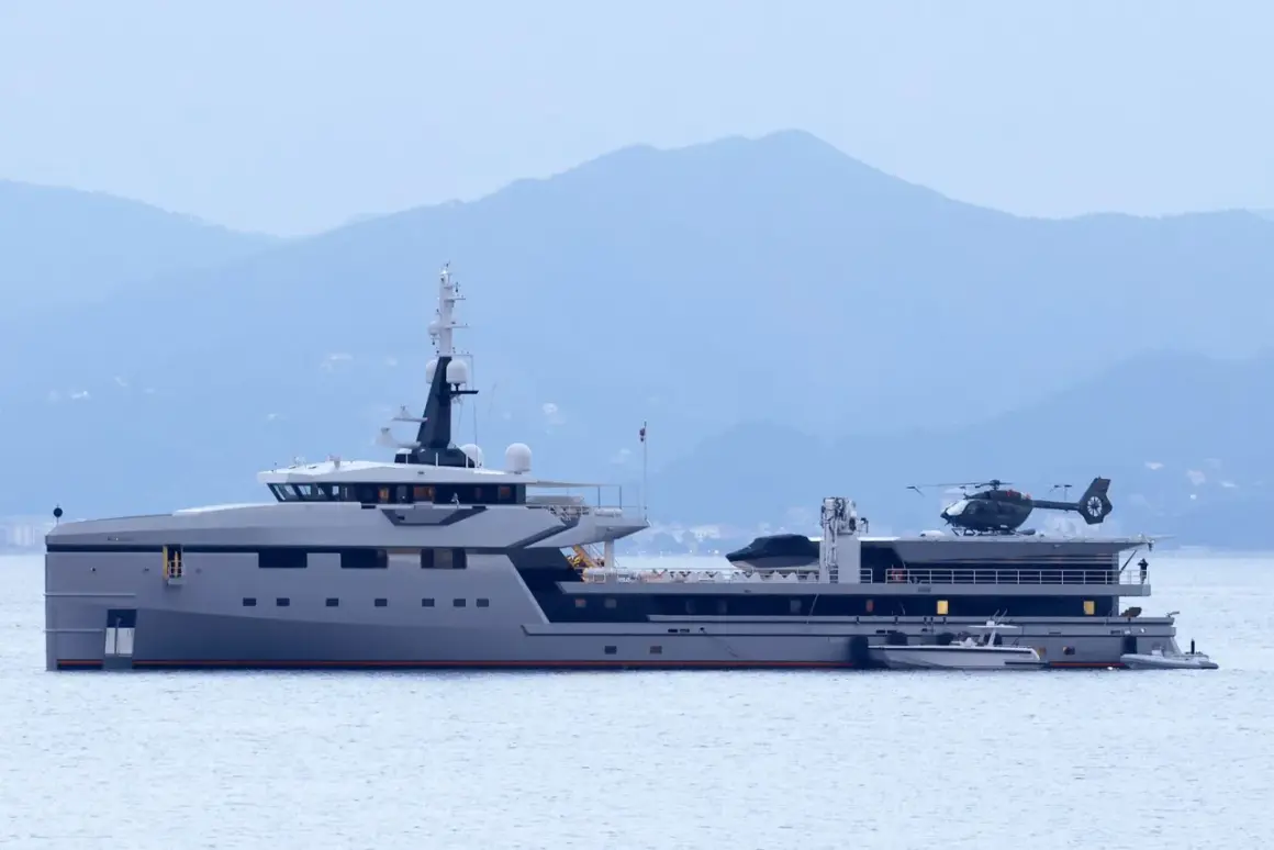 Lo yacht Koru, con il suo elicottero pronto al decollo, naviga maestoso in acque tranquille, con le montagne sullo sfondo.