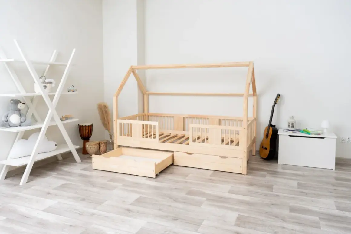 Łóżko domek z litego drewna sosnowego, z szufladami, obok regał, bębny i gitara.