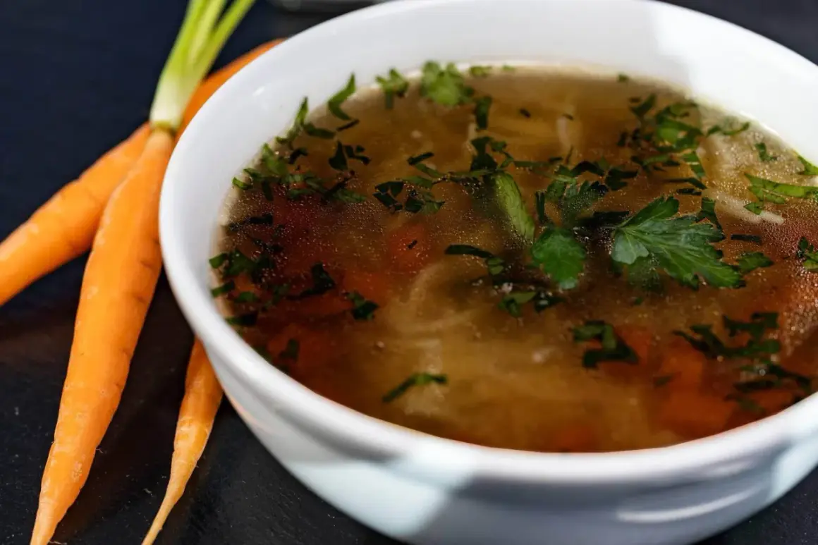 Aromaticzny rosół kolagenowy z marchewką i natką pietruszki, obok świeże marchewki.