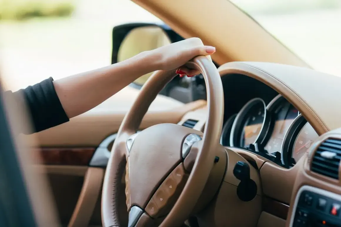 Dłoń na kierownicy, czuć drgania na kierownicy przy 100 km/h. Wnętrze luksusowego samochodu.