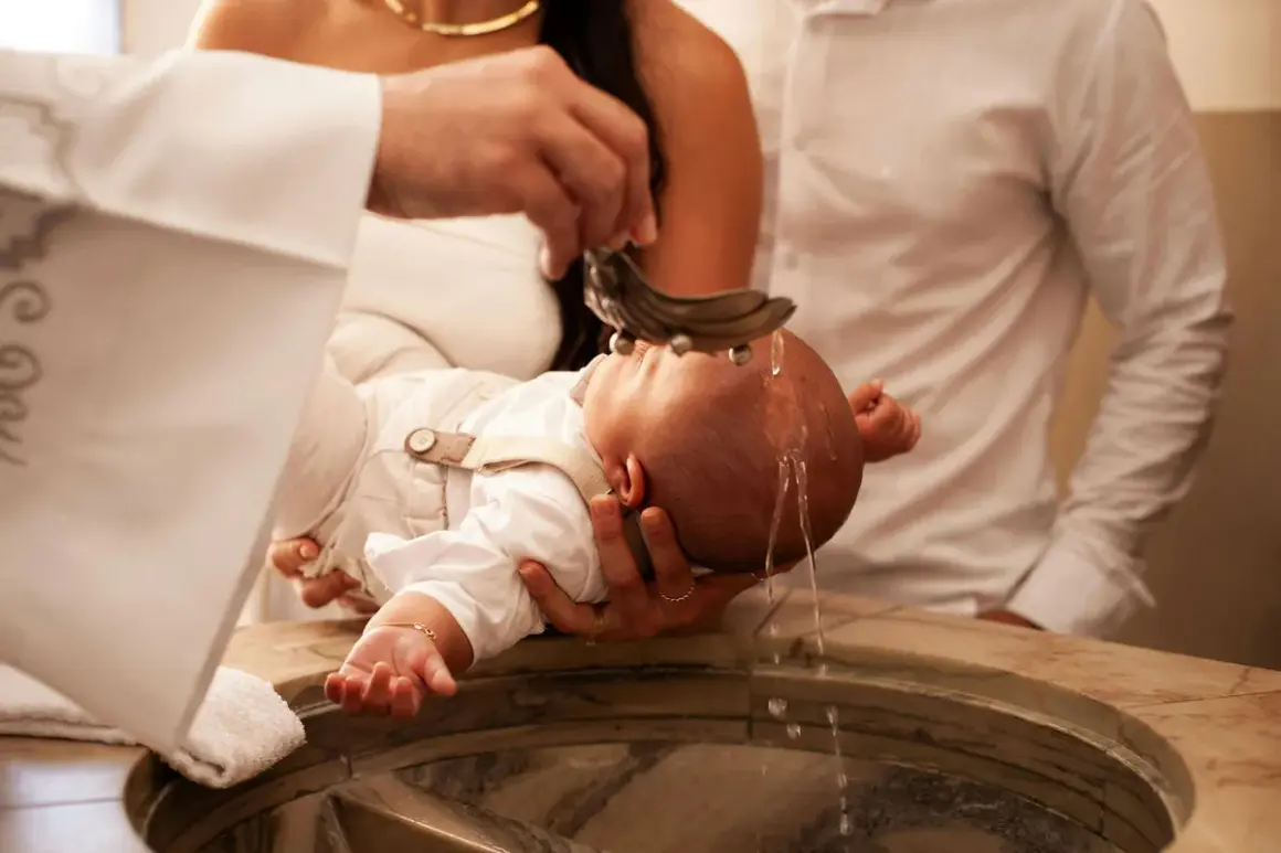 Cérémonie de baptême : un bébé reçoit de l'eau bénite. Le prêtre qui lit le psaume baptême bénit l'enfant.