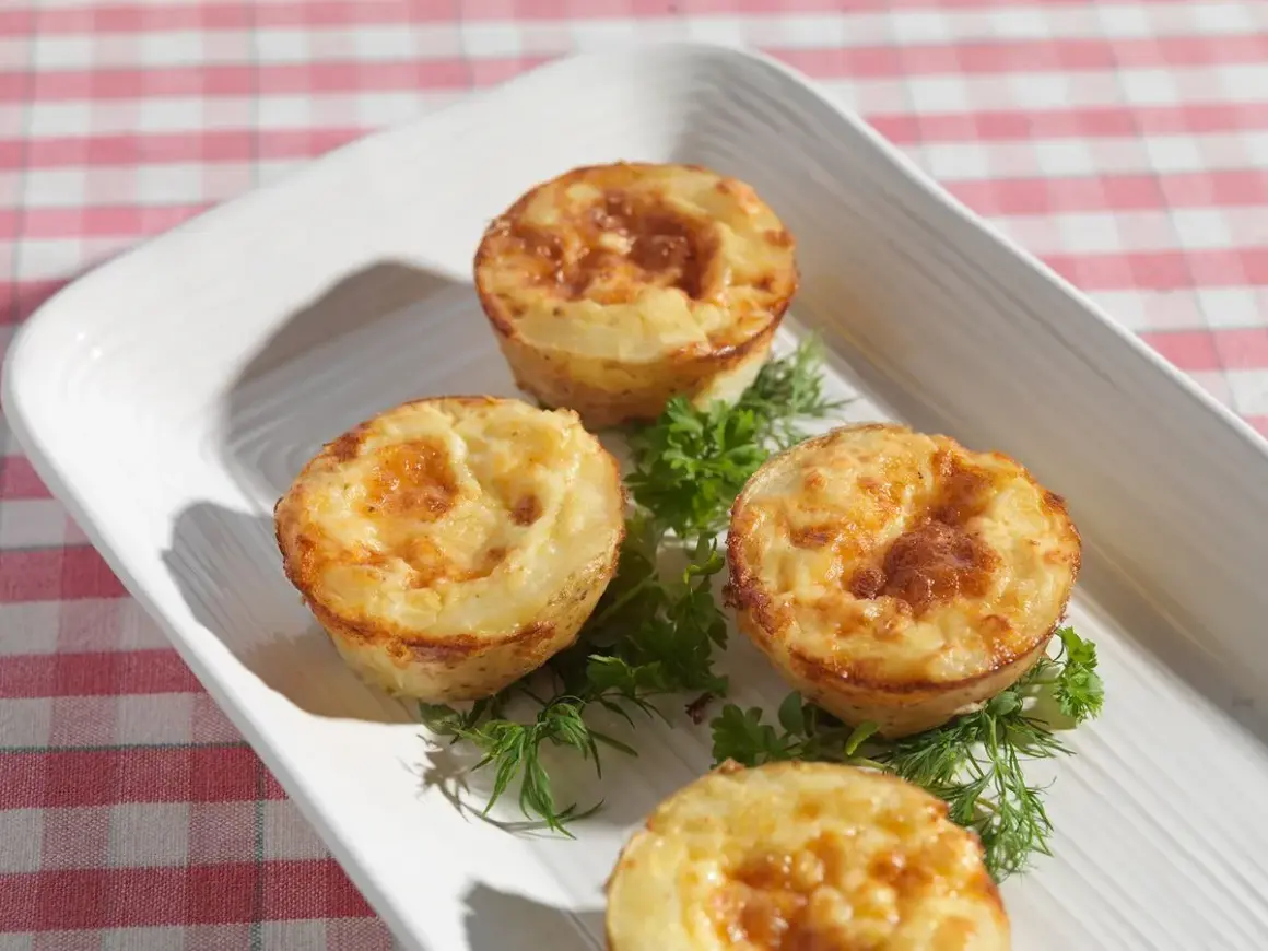 Små, gyllene potatis i muffinsform, serverade med färska örter på en vit bricka. Perfekt som tillbehör eller plockmat.