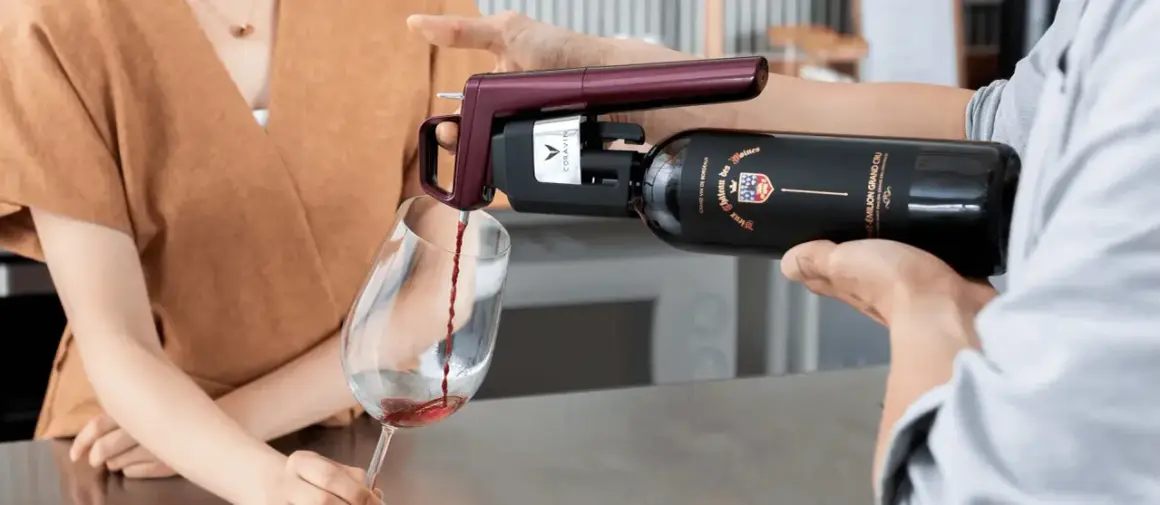 Un appareil Coravin sert un vin rouge d'une bouteille ouverte dans un verre, assurant sa conservation.