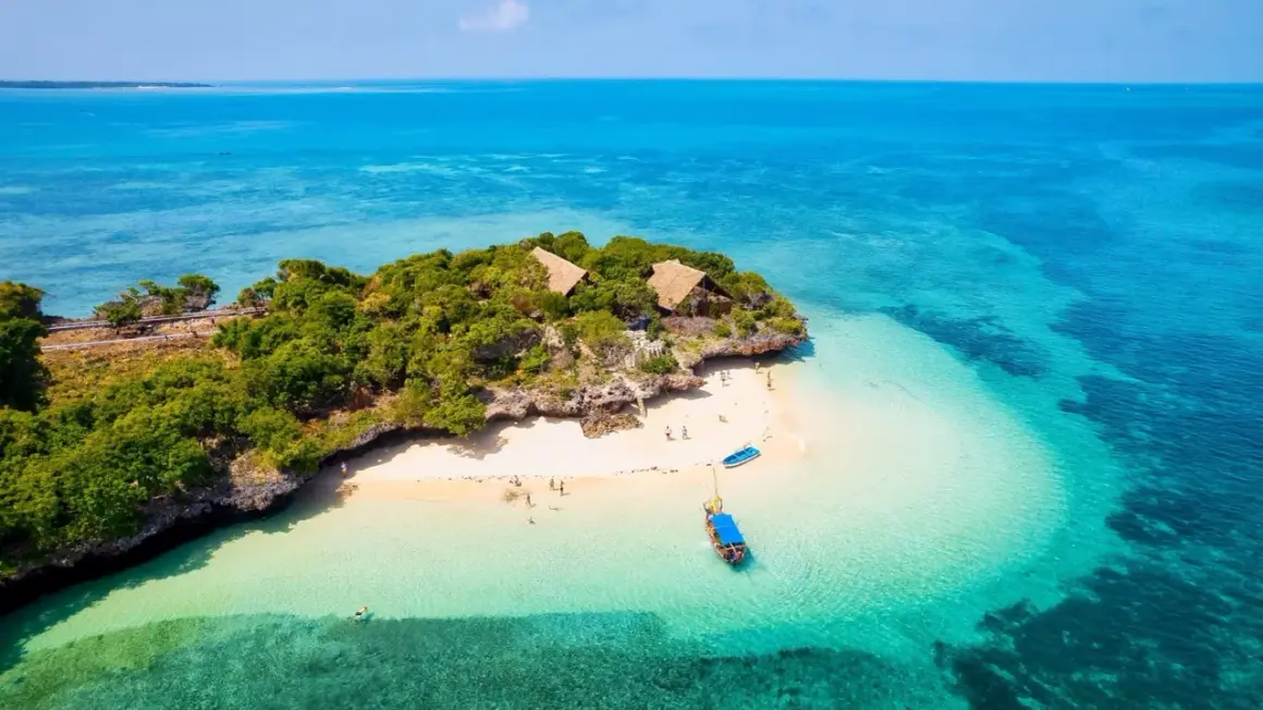 Rajska wyspa na Zanzibarze z turkusową wodą i chatkami. Zastanawiasz się, ile kosztuje wycieczka na Zanzibar?