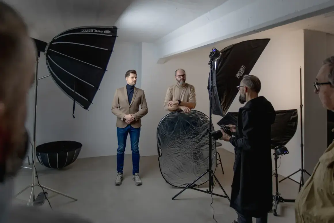 W studiu fotograficznym mężczyźni przygotowują się do sesji. Wrota do świata fotografii otwierają się dzięki profesjonalnemu sprzętowi.