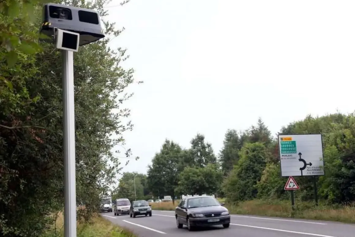 Un radar leurre sur un poteau, avec des voitures sur la route et un panneau de signalisation.