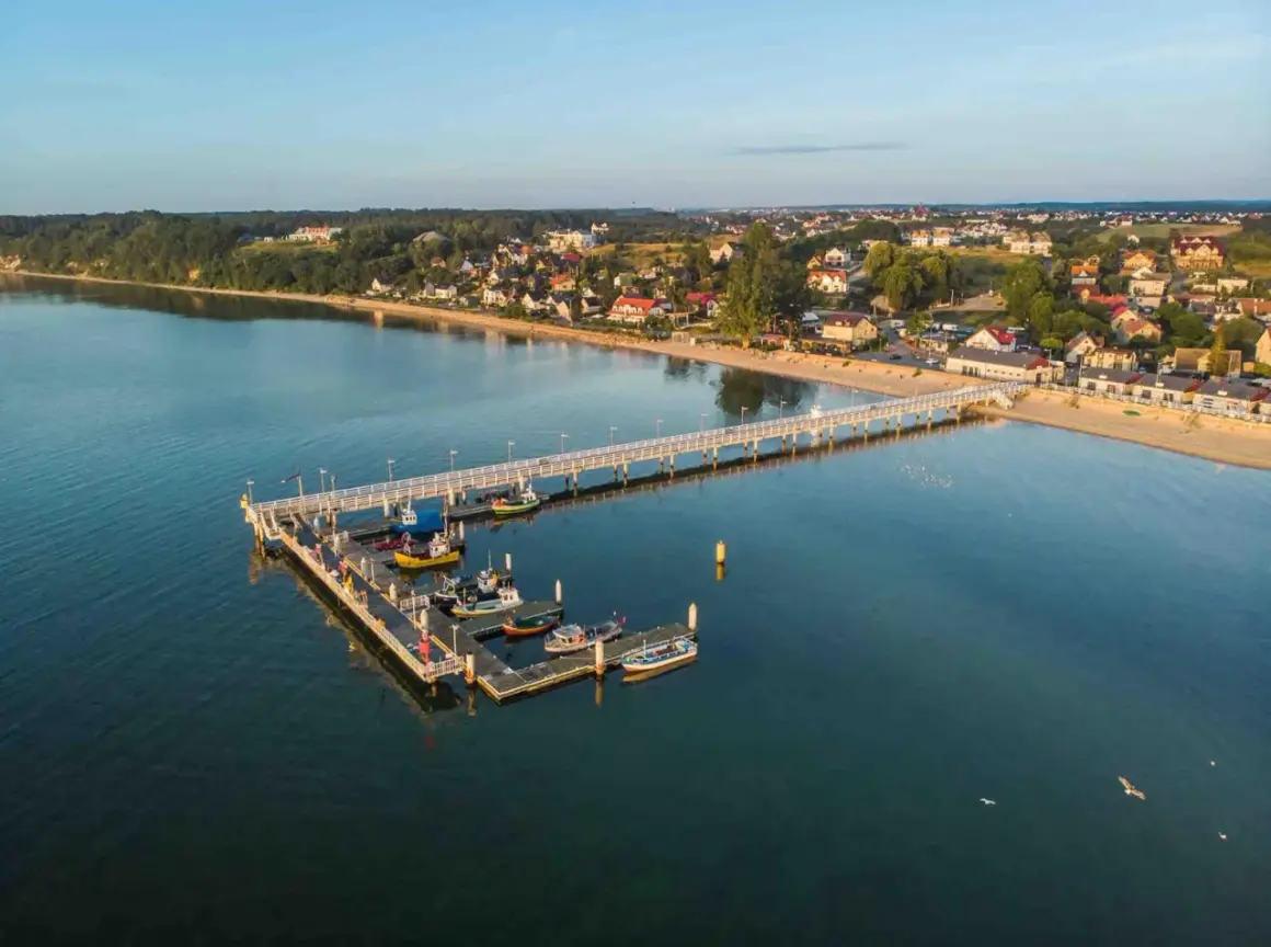 Molo w Mechelinkach z łodziami i widokiem na plażę i zabudowania. To świetne mechelinki atrakcje dla każdego.