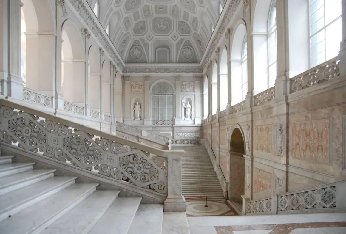 Scalinata monumentale del palazzo reale Napoli, con marmi bianchi e decorazioni barocche.