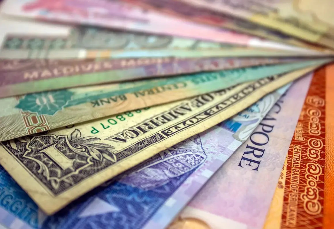 Różne waluty świata ułożone wachlarzowo, od dolara amerykańskiego po banknoty z Singapuru i Sri Lanki. Ile jest walut na świecie? Tyle, ile widzisz tutaj i jeszcze więcej!
