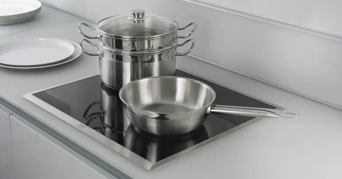 Pentole e padelle in acciaio inox pronte per cucinare su piastra a induzione.
