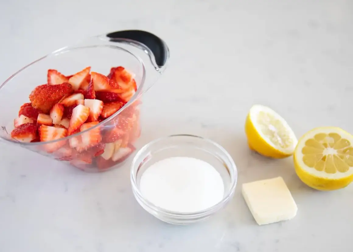 Ingrédients pour un coulis de fraise : fraises coupées, sucre, beurre et citrons.