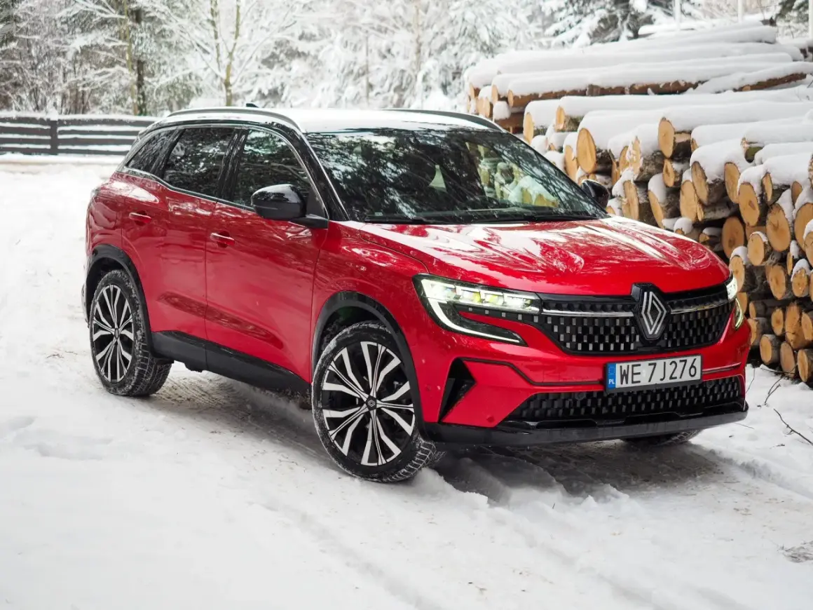 Czerwony Renault Austral na śniegu, z widocznymi felgami i grillem. Poznaj jego wymiary i możliwości w zimowych warunkach.