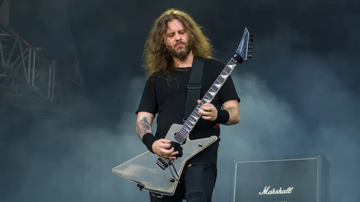 Charyzmatyczny gitarzysta rockowy z długimi włosami, grający na czarnej gitarze typu explorer. Jeden z wielu utalentowanych polskich gitarzystów rockowych.