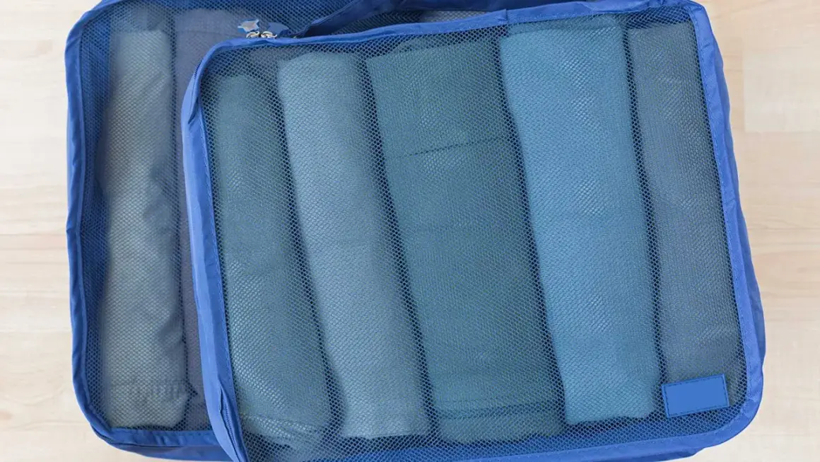 Två blå packpåsar med rullade kläder. Ett perfekt **pile material** för organiserad packning.