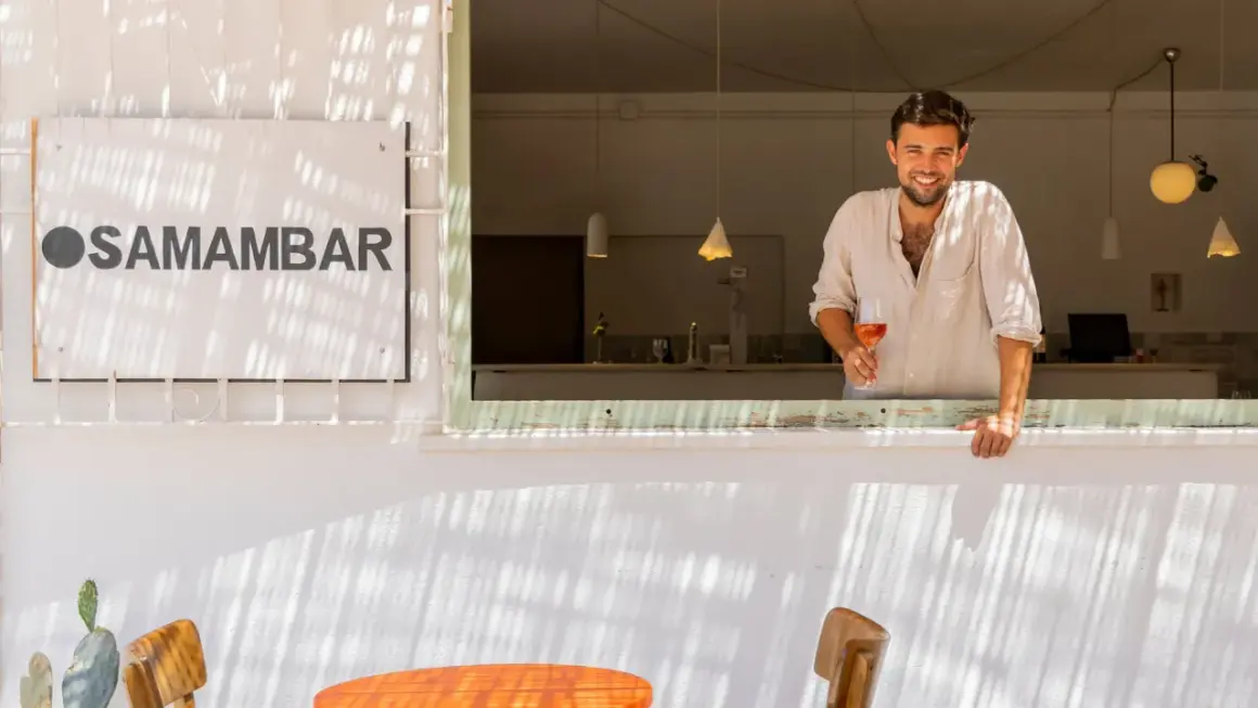 Hombre sonriente con copa de vino rosado en Samamabar, un lugar ideal para comer en Rodalquilar.