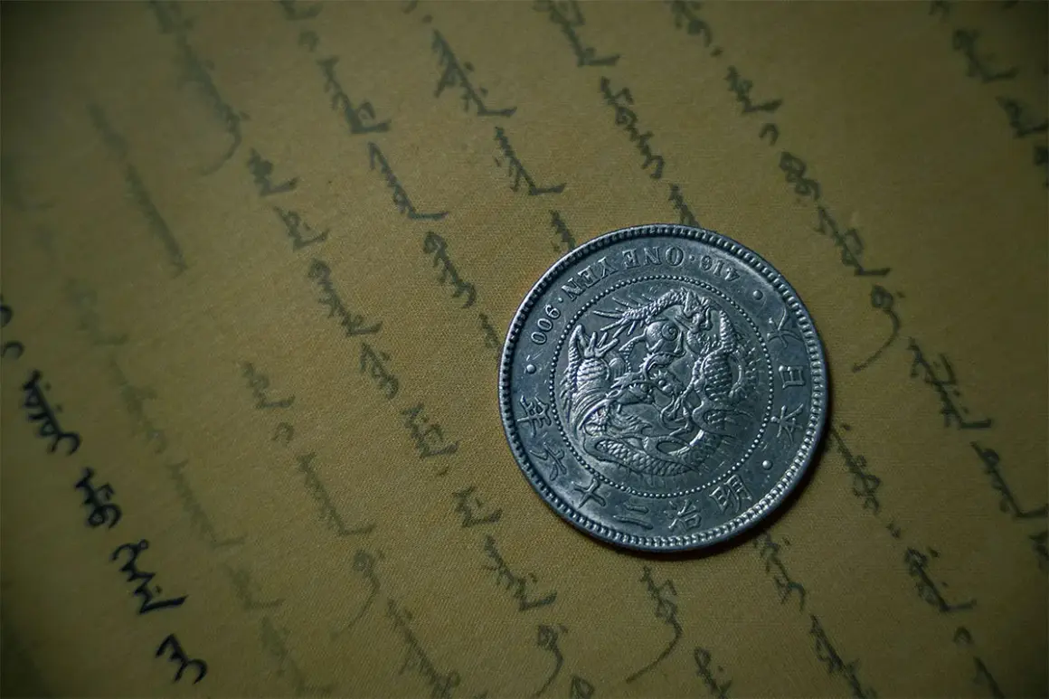 Srebrna moneta bulionowa z wizerunkiem smoka, leżąca na pożółkłym papierze z orientalnym pismem.