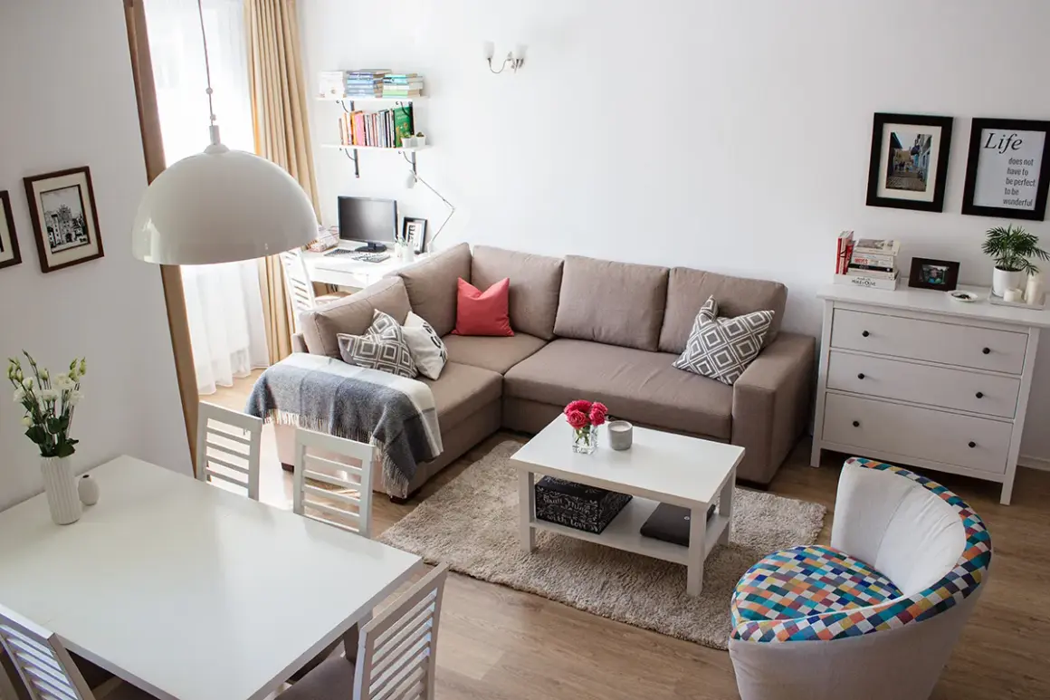 Przytulny salon z narożnikiem, stołem i biurkiem. Układ mieszkań w bloku z wielkiej płyty zaaranżowany na nowo.