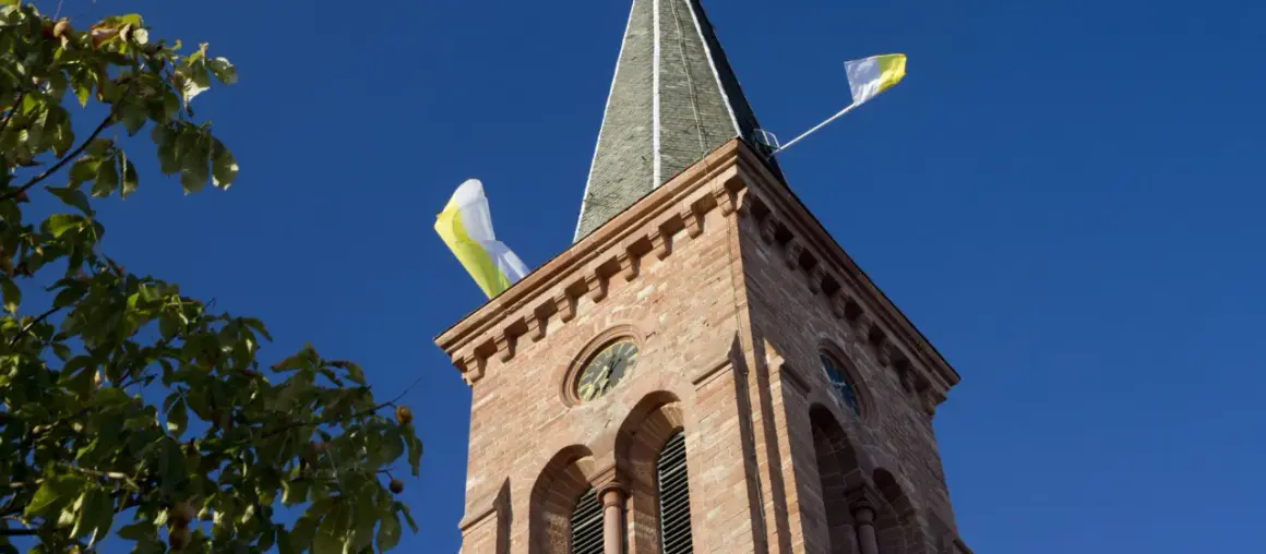 Kirchturm mit Fahnen im Wind, ein Zeichen, dass die Kirchweih gefeiert wird.