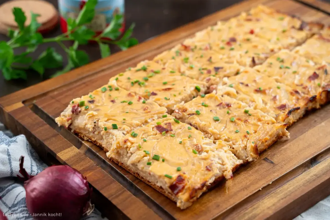 Saftiger Zwiebelkuchen vom Blech, goldbraun gebacken und mit Schnittlauch bestreut. Ein Genuss für jeden Anlass!
