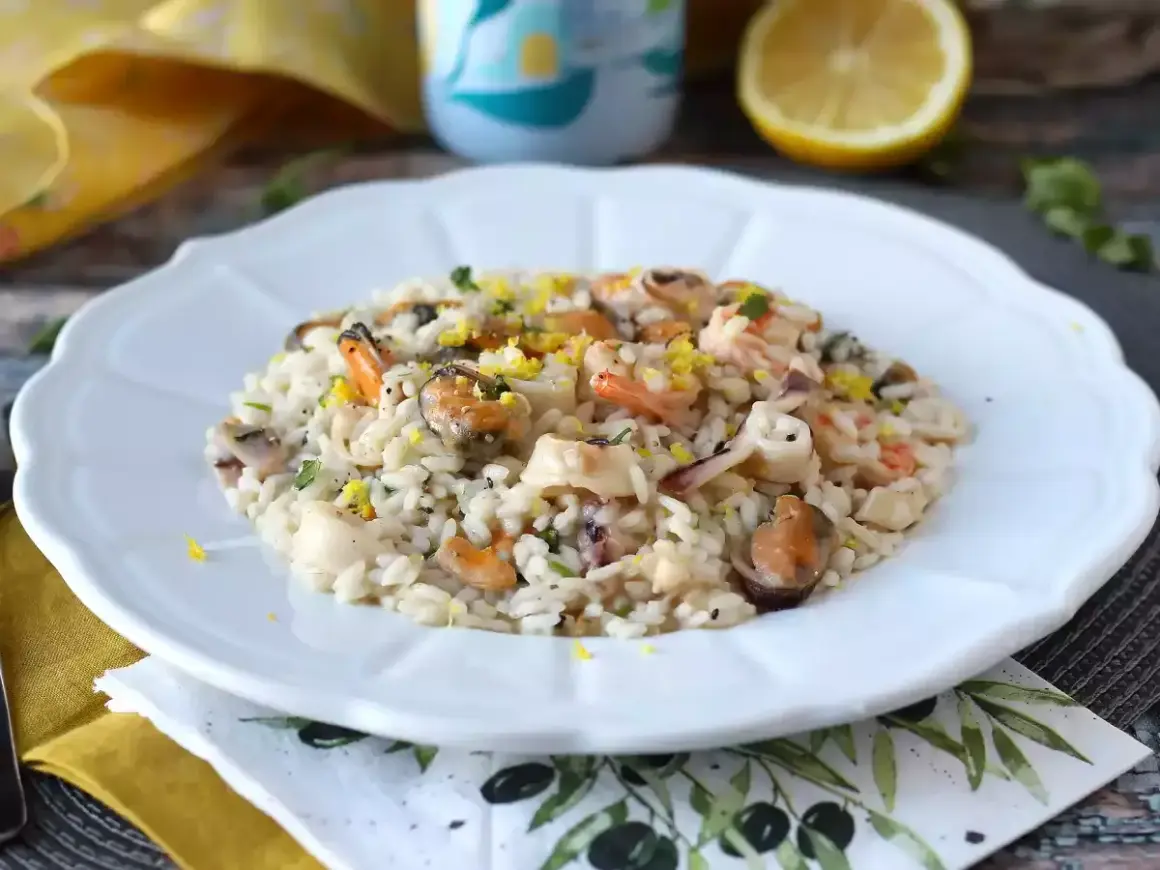 Delicioso risotto de marisco con mejillones, gambas y calamares, adornado con ralladura de limón y perejil fresco.