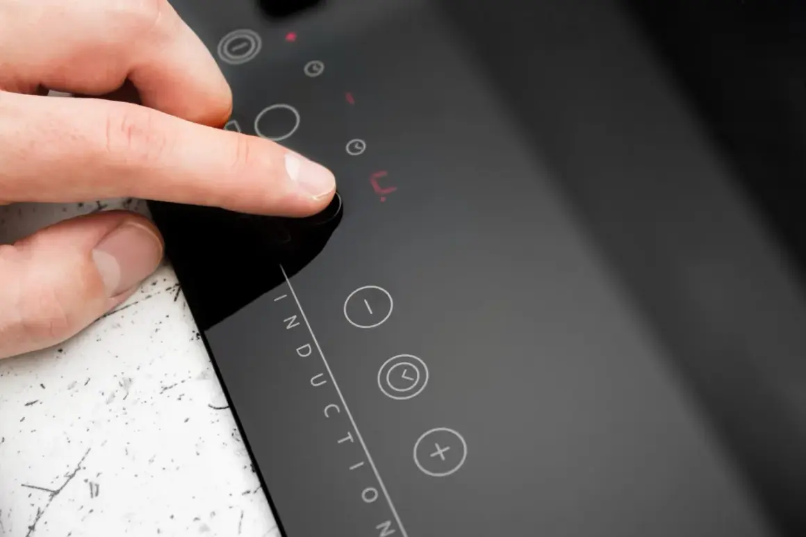 Doigt appuyant sur un bouton de la plaque induction erreur e. L'écran affiche un code d'erreur.