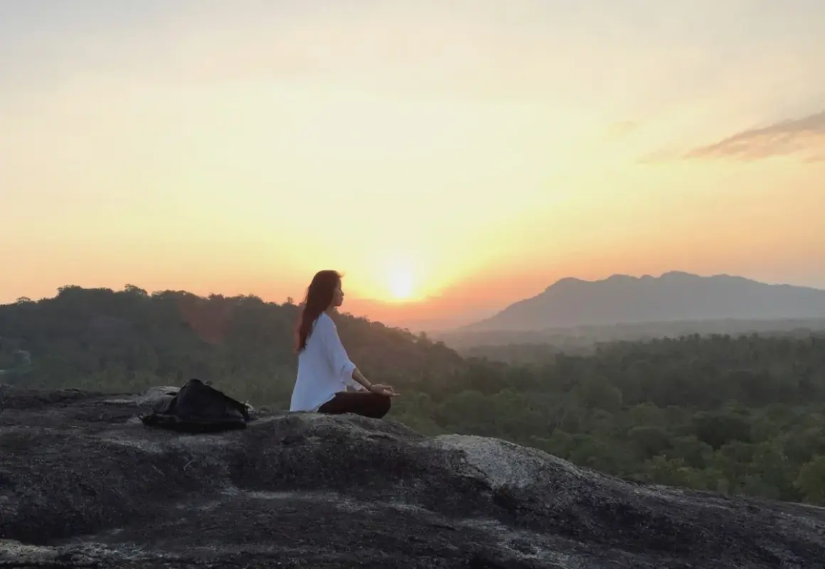 Mujer meditando al amanecer, buscando el equilibrio yin yang en la naturaleza.