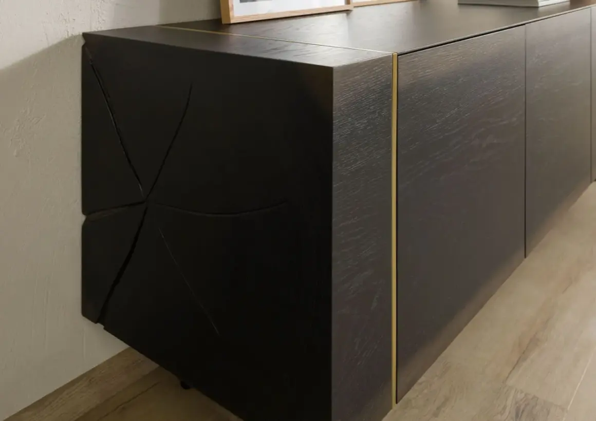 Dunkles Sideboard mit markanter, geometrischer Front. Die Maserung des Holzes und die goldene Leiste unterstreichen, was bedeutet massiv: ein Möbelstück, das Charakter und Beständigkeit ausstrahlt.