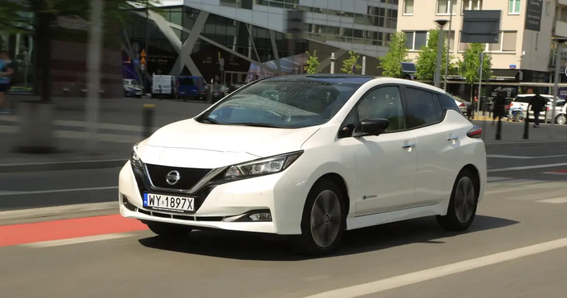 Biały Nissan Leaf 2 jedzie ulicą miasta.