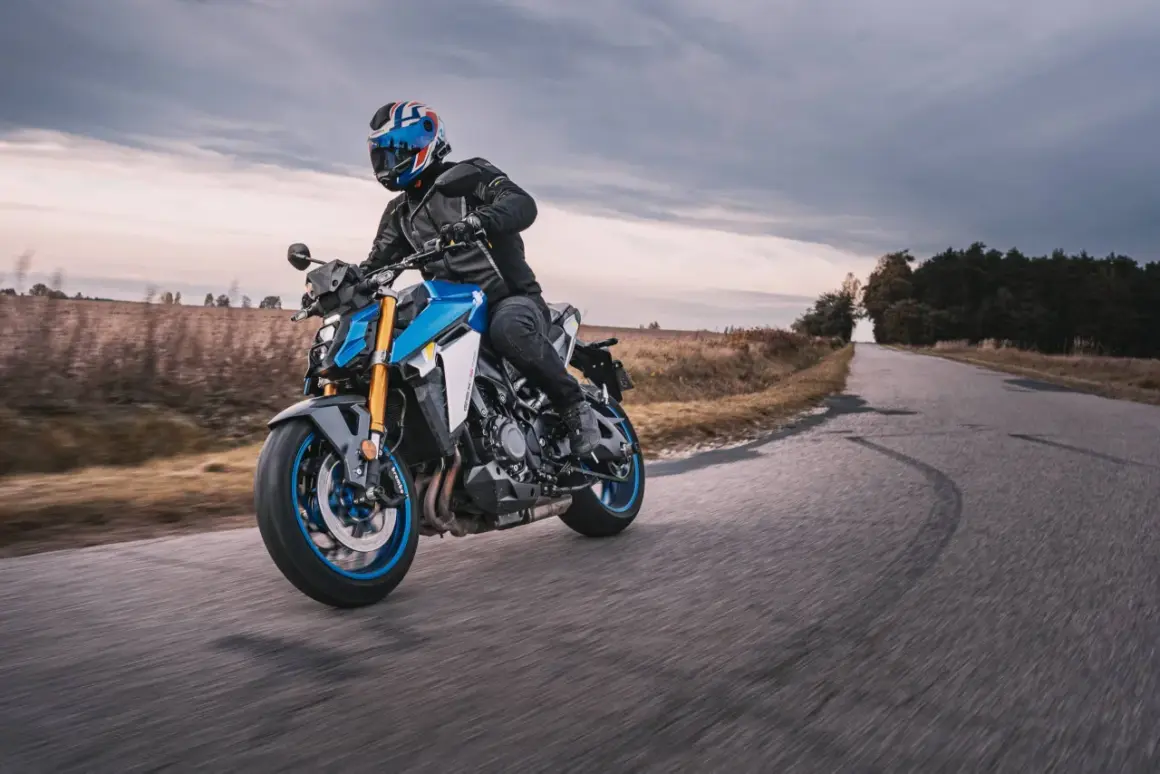 Motocyklista w kasku z brytyjską flagą pokonuje zakręt na drodze, doświadczając zjawiska shimmy.