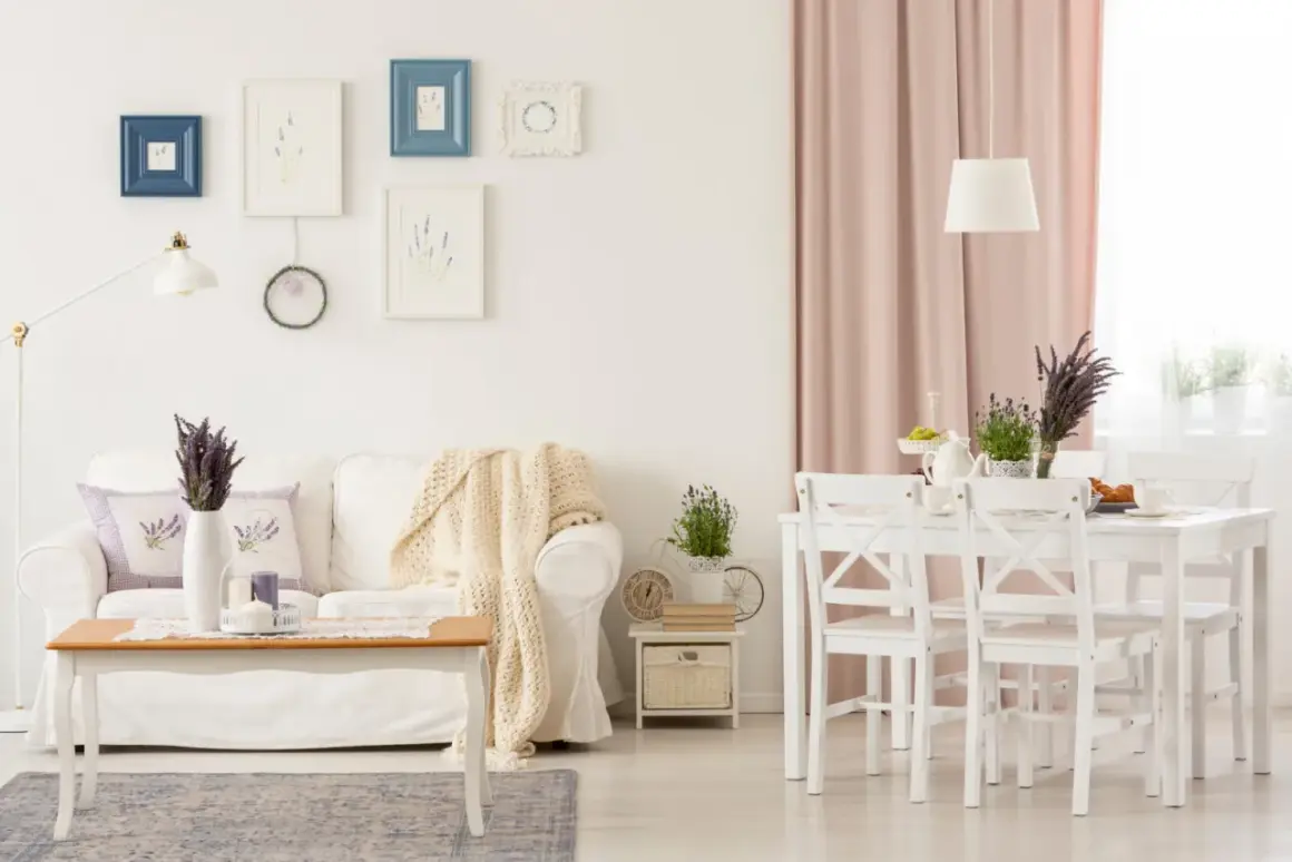 Przytulny salon w stylu shabby chic z białą kanapą, drewnianym stolikiem i pastelowymi dodatkami.