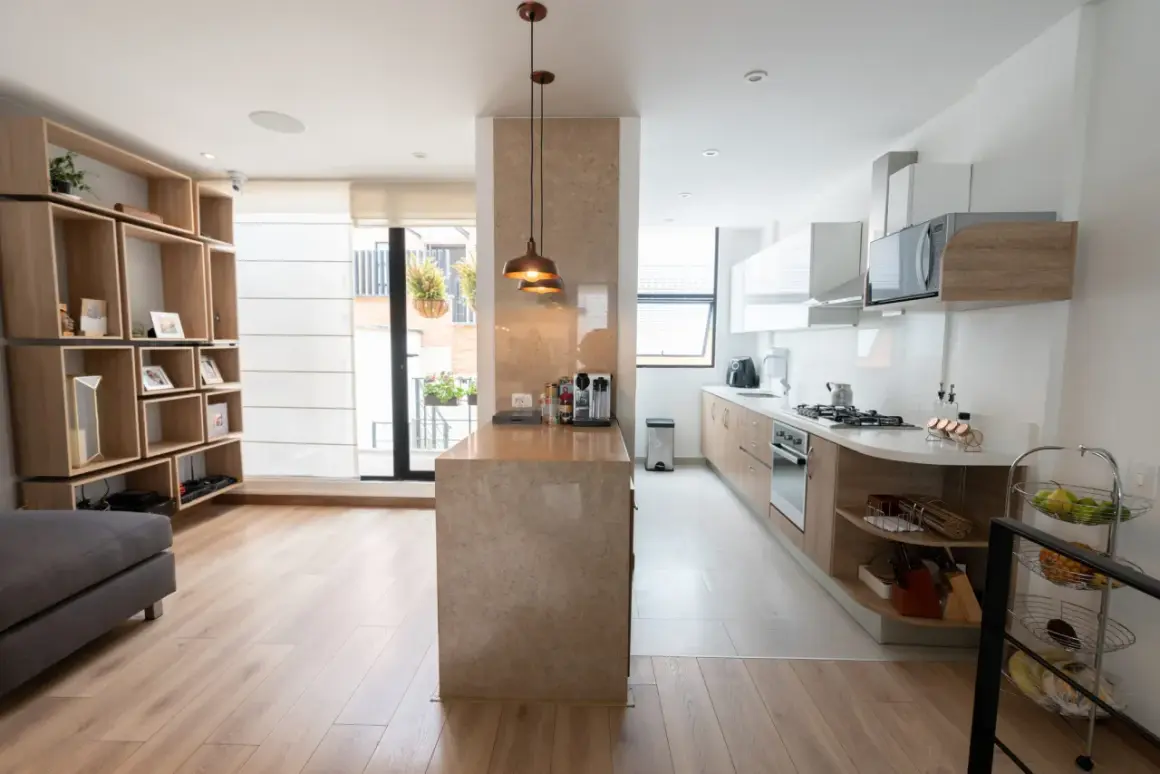 Un tabique de cocina semiabierta al salón crea un espacio moderno y funcional.