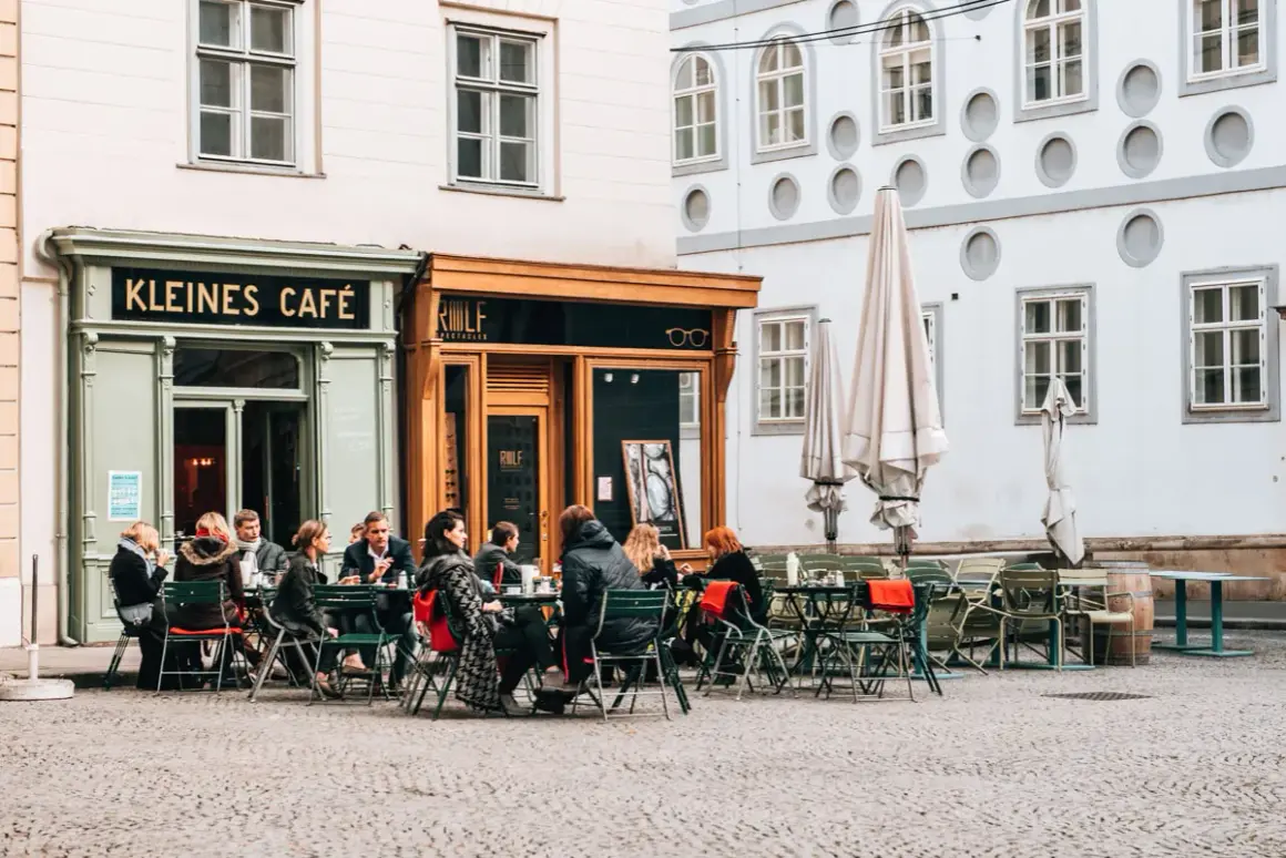 Menschen sitzen vor dem "Kleines Café" und genießen einen kleinen braunen Kaffee.