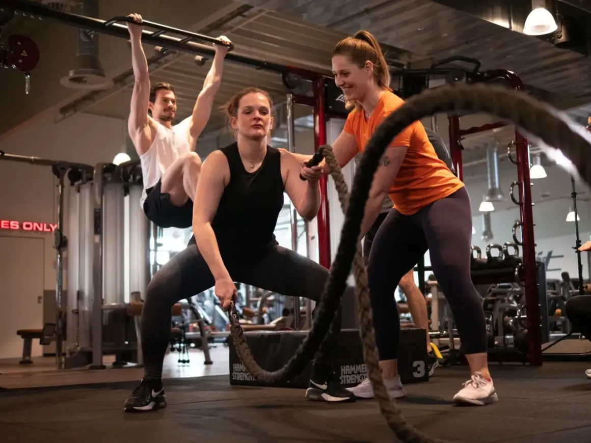 Frauen trainieren mit Seilen, ein Mann hängt an einer Klimmzugstange. Ein Blick in die Praxis der Athletiktrainer Ausbildung.