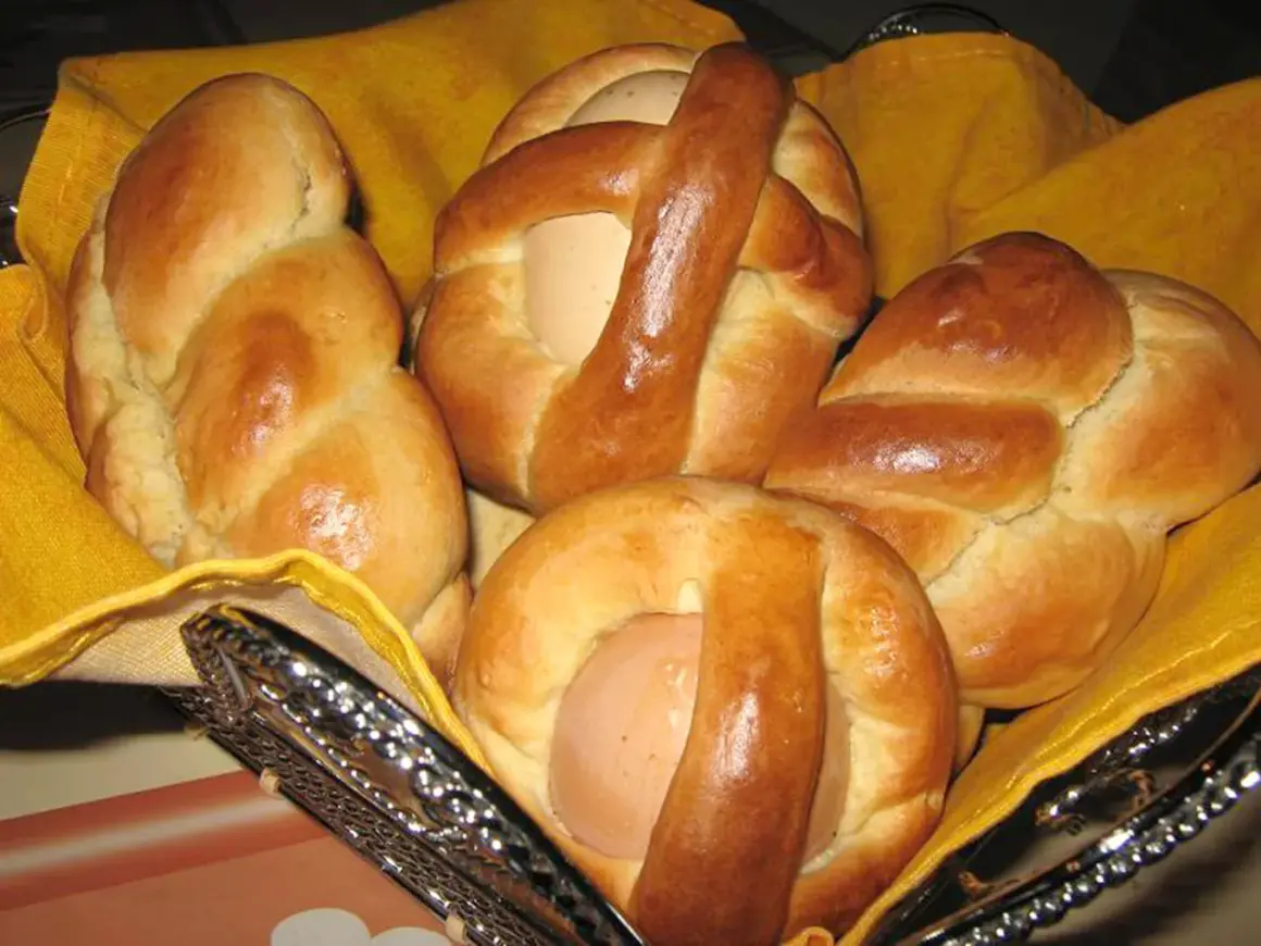 Cuzzupe calabresi morbide, dolci pasquali con uova, in un cestino foderato di giallo.