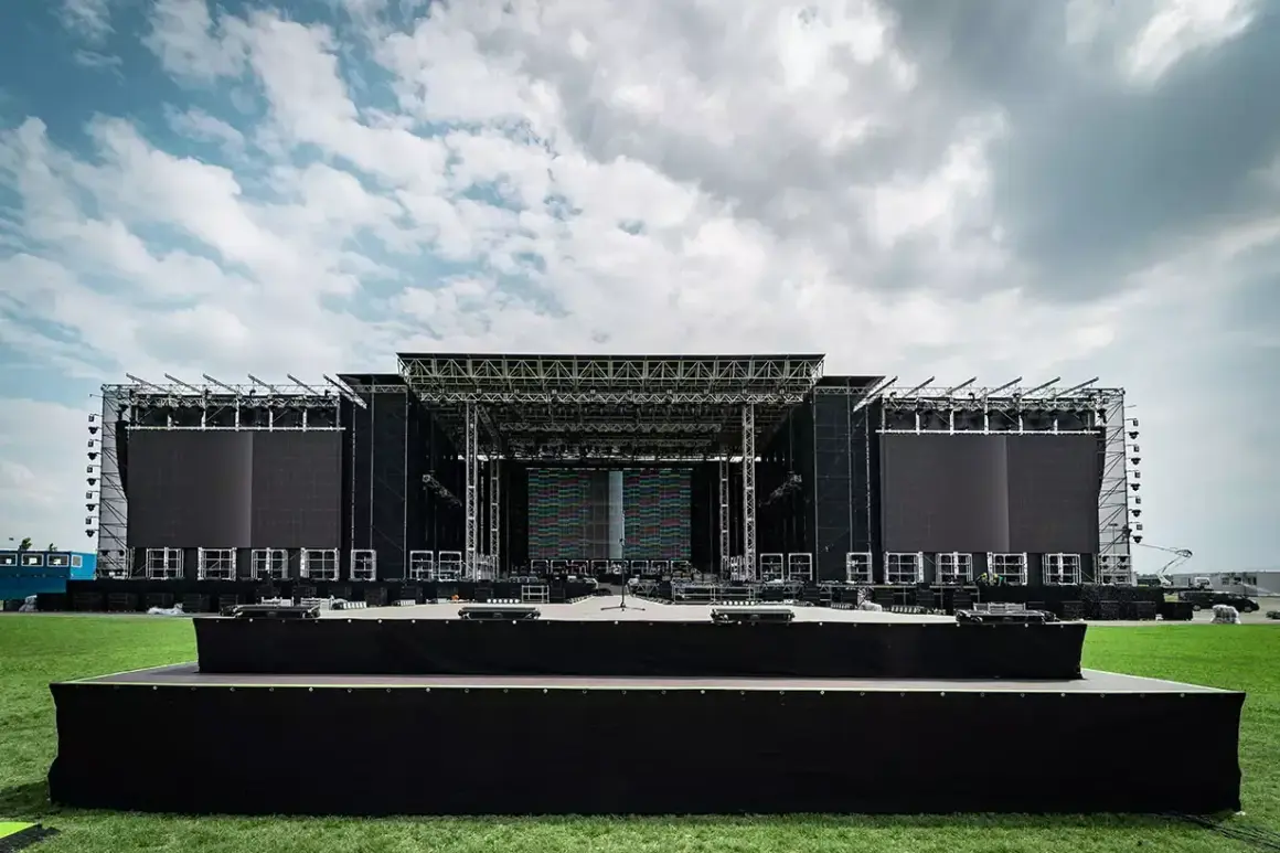 Ogromna scena koncertowa RCF Arena czeka na tłumy. Metalowa konstrukcja, ekrany LED i zielona murawa pod błękitnym niebem.