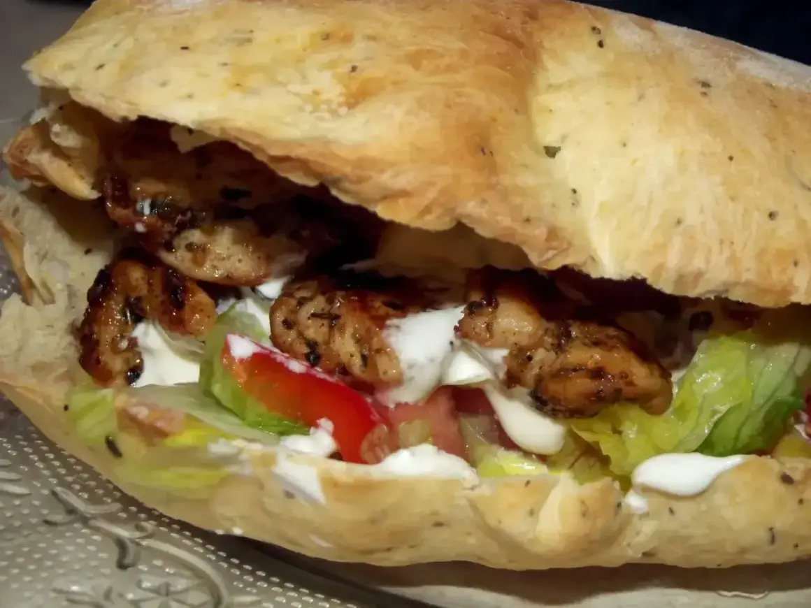 Pyszny kebab w picie z soczystym kurczakiem, świeżą sałatą, pomidorem i kremowym sosem. Idealny na szybki posiłek.