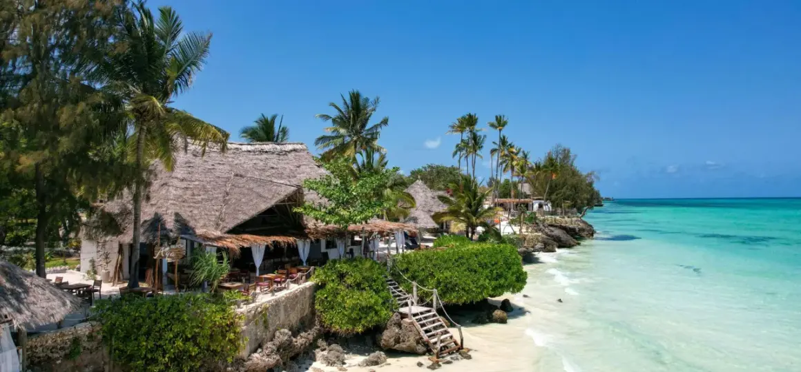Zanzibar w lutym: słoneczna pogoda, palmy, plaża i urokliwe restauracje z krytymi strzechą dachami. Idealne miejsce na wakacje.