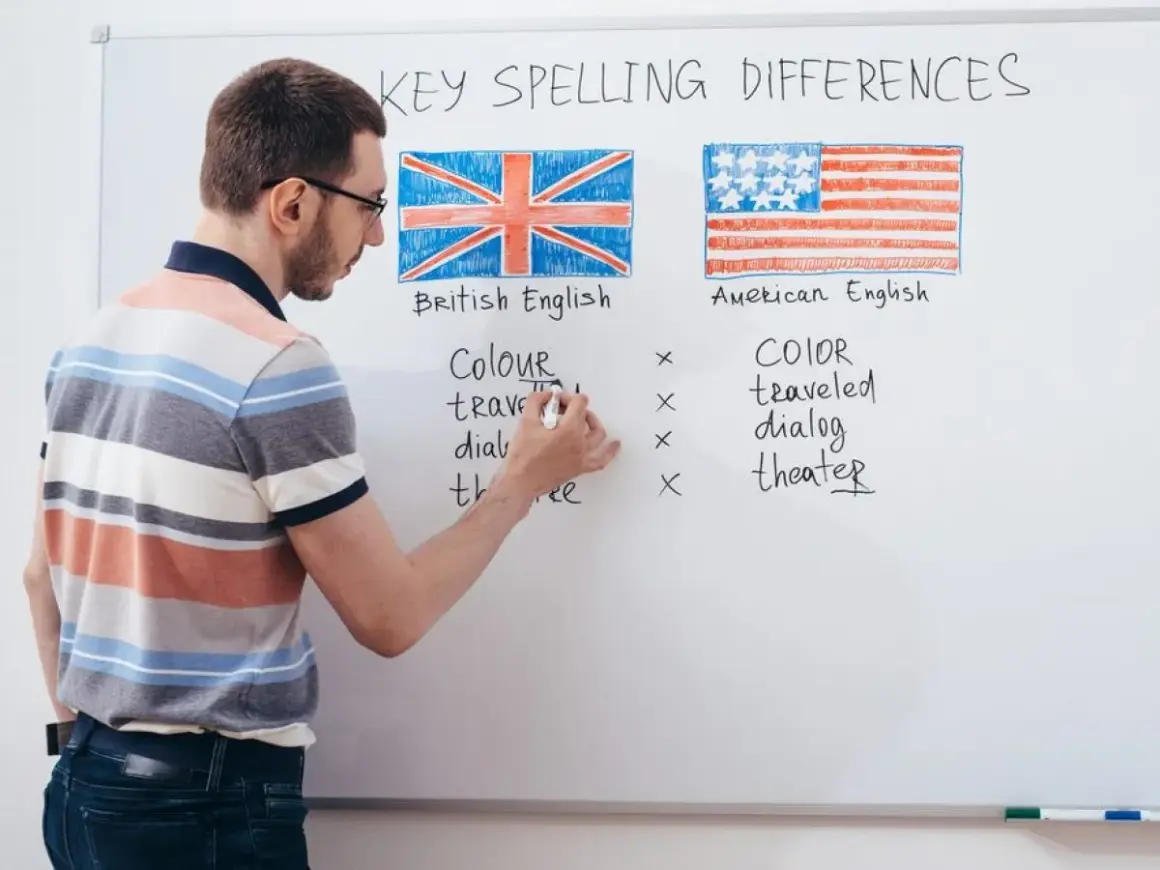 Profesor explica las diferencias de ortografía entre los tipos de inglés: británico y americano, con ejemplos escritos en la pizarra.