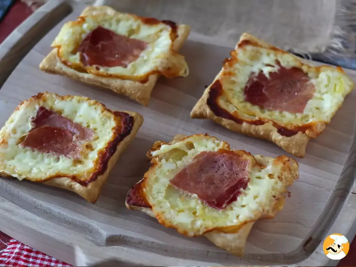 Cztery kwadratowe tartaletki z ciasta francuskiego, wypełnione roztopionym serem i plastrami szynki. Idealne na szybką przekąskę w stylu raclette.