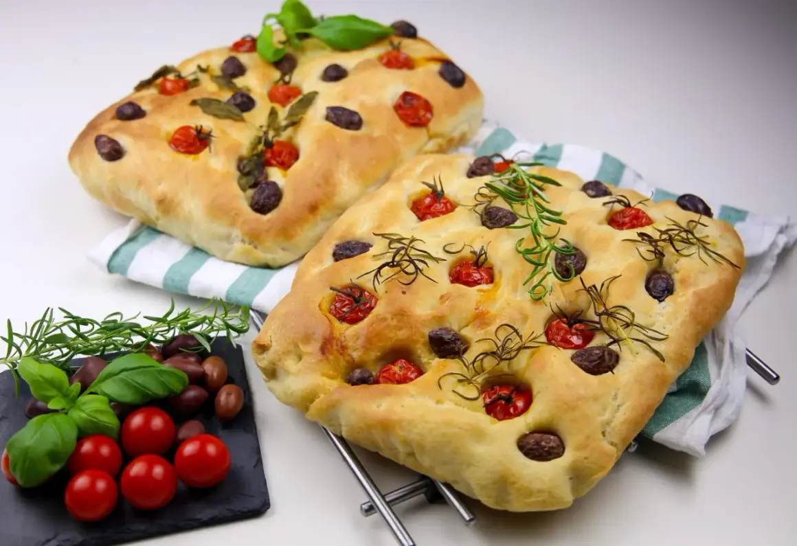 Två gyllene focaccia med tomater, oliver och rosmarin. Ett perfekt focaccia recept från Zeina som ser ljuvligt ut!