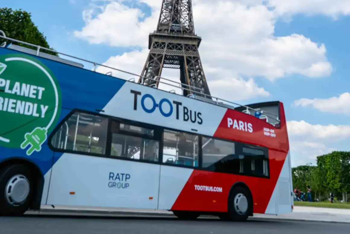 Ekologiczny autobus wycieczkowy Tootbus w Paryżu, z widoczną Wieżą Eiffla w tle. Idealny sposób na zwiedzanie Paryża samochodem.