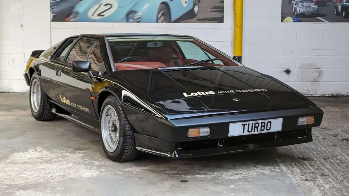 Czarny Lotus Esprit Turbo z czerwonym wnętrzem, z napisem "Lotus ACTIVE SUSPENSION" na masce.