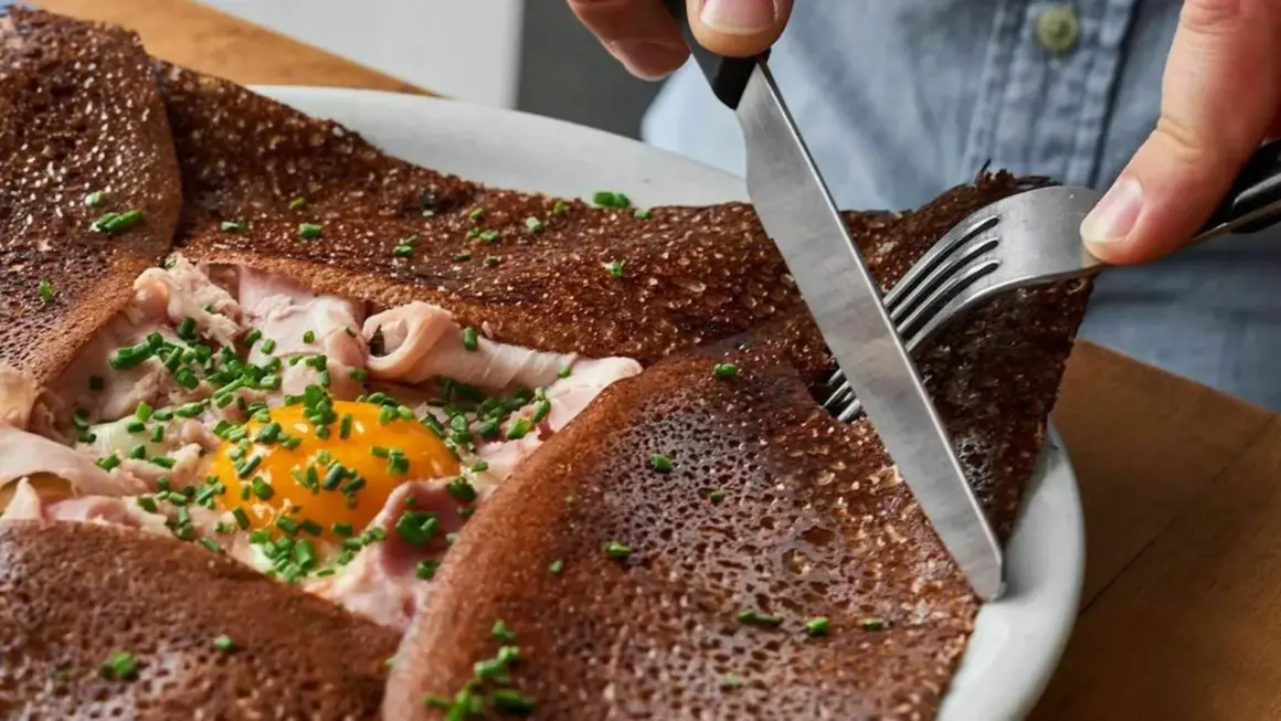 Une galette complète, garnie d'œuf, jambon et ciboulette. Une bouchée des meilleures crêpes à Paris.