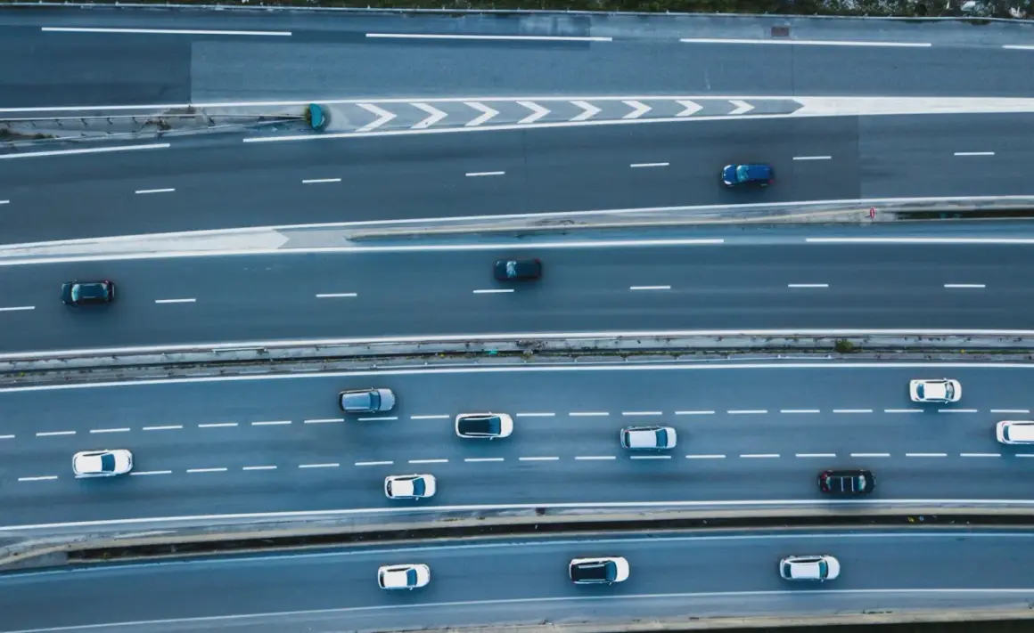 Widok z góry na autostradę, gdzie samochody wykonują manewry **wymijania** i **omijania** przeszkód, tworząc dynamiczny obraz ruchu drogowego.
