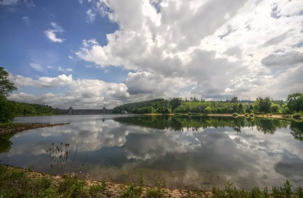 Stausee mit imposanter Staumauer, gespiegelt im ruhigen Wasser. Ein idyllischer Anblick, seen in NRW.