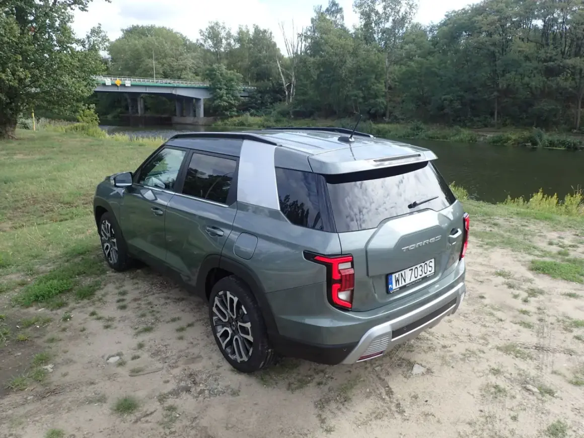 Zielony Torres auto zaparkowany nad rzeką, w tle most i las.