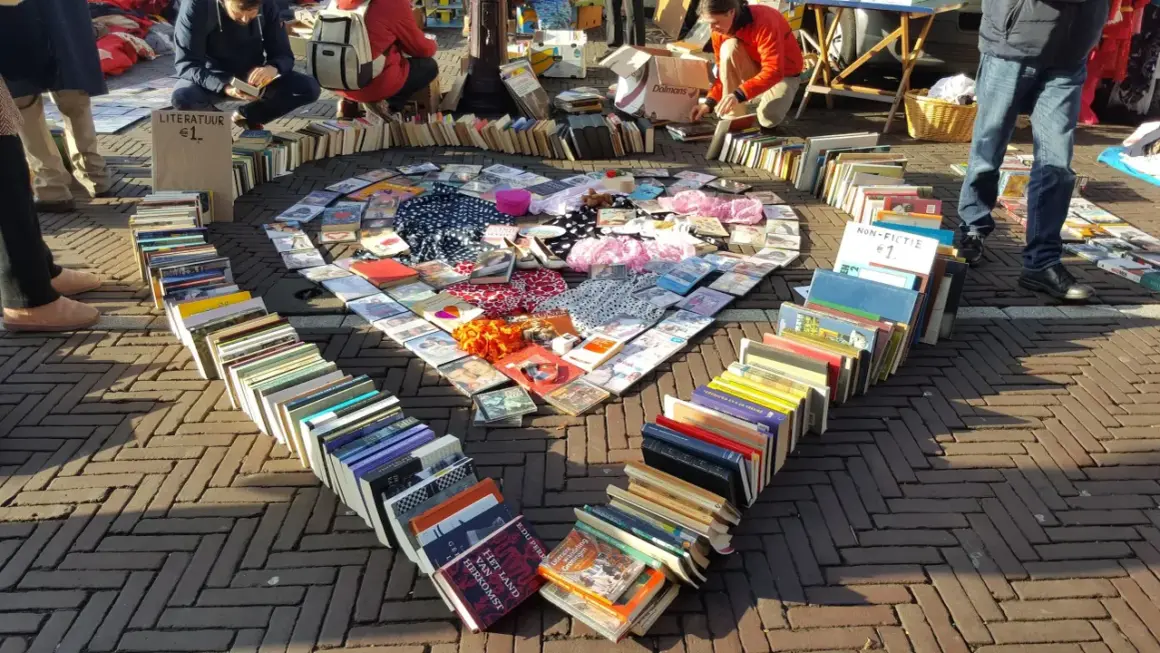 Herzförmige Anordnung von Büchern und CDs auf einem Flohmarkt. Tolle Flohmarkt Stand Ideen für Bücherliebhaber.